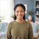 Headshot of a smiling woman with warm eyes against a soft, blurred background in blue and white tones.