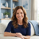 A smiling middle-aged woman in a bright, modern home setting, representing a satisfied customer.